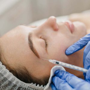 Closeup portrait injection on face of pretty woman during botox procedures in salon. Professional work, hands in blue gloves, doctor, rejuvenation, modern medicine, making beauty, healthcare